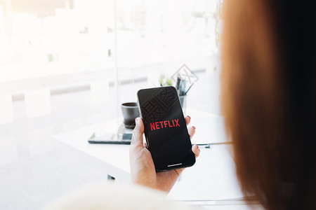 2020全球算力大会2020年12月 女性手持智能电话 在苹果iPhone Xs上印有Netflix标志 Netflix是全球流动电影和电视系列的提背景