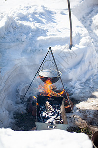 雪火火上挂着一个煮饭的锅食物篝火午餐背包火焰旅行冒险锅炉摄影活动背景