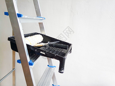 白色梯子墙壁修理 白色背景的黑托盘中继板 滚滚机和刷子背景