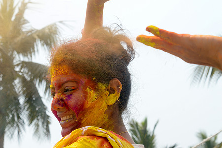 兰戈里粉在 Holi 色彩节期间 一位年轻的印度快乐女人的肖像 脸上涂着粉黄色和红色的 Holi 彩色粉末涂料 正视图 看着相机乐趣色彩背景