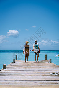 荷属阿鲁巴岛阿鲁巴加勒比棕榈海滩 在阿鲁巴有棕榈树的白长沙沙滩度假村码头奢华天蓝色蜜月假期旅行男人女士异国背景