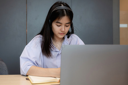 做笔记的女孩亚洲学生在家用笔记本电脑在线课程中做笔记的亚洲学生女孩学校视频工作成人女士教育大学休闲装互联网背景