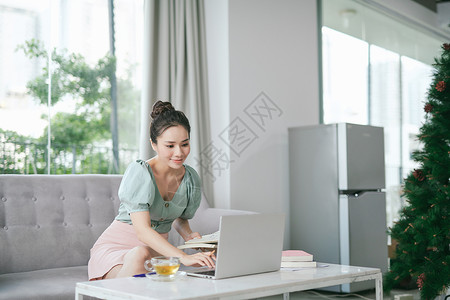 在家工作的妇女 有吸引力的女士持有文件和写作 坐在沙发上 用笔记本电脑 免费空间背景图片
