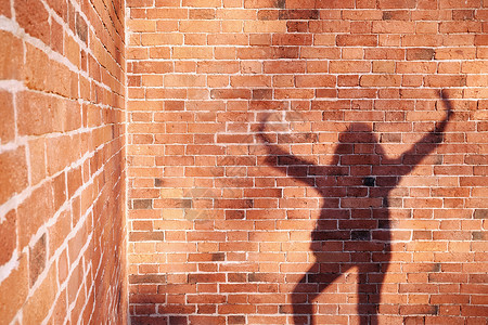 舒克桑手臂一个人在砖墙背景上的影子阳光城市公园长发场景成人女孩垂直红砖男人背景