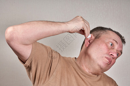一个男人用药瓶里的小管子 将药品灌进他的耳朵里滴水医疗治愈保健耳炎药剂成人感染护理卫生背景图片