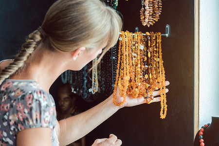卖珠宝素材女人看着一条由琥珀制成的项链售货员宝石店铺帮助文员珠宝石头服务女士作坊背景
