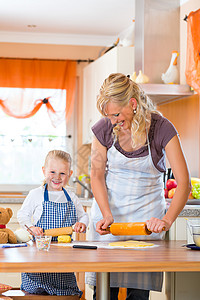 穿围裙母亲母亲和女儿一起烤饼干的蛋糕糕点糖果商女孩喜悦厨房贡献孩子女士烘烤面包背景