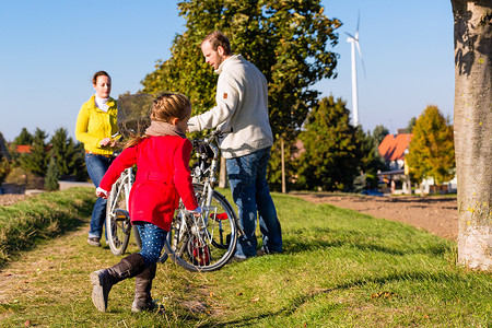 骑三轮带孩子的父亲参加公园自行车旅游的家庭木头男人女士孩子们母亲国家微笑爸爸孩子旅行背景