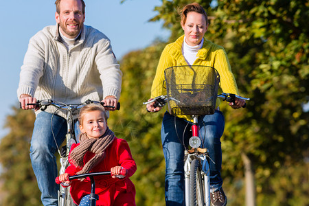 骑三轮带孩子的父亲参加公园自行车旅游的家庭国家生活女儿旅行妈妈微笑男人孩子母亲爸爸背景