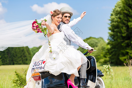 自行车上恋人刚结婚 在摩托摩托车上结了婚裙子夫妻驾驶蜜月礼帽花园男人国家树木乡村背景