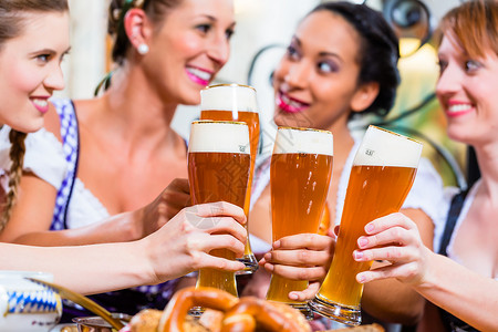 女孩在巴伐利亚酒吧用小麦啤酒烤面包传统食物女士餐厅女性团体黑色朋友们少女装客栈背景图片
