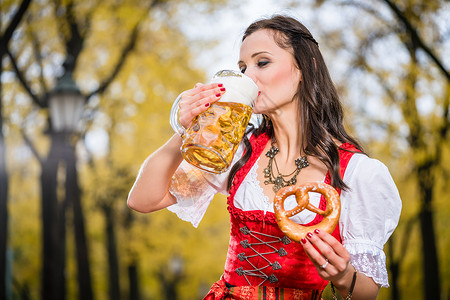 传统巴伐利亚保守派女孩 用大杯子喝啤酒饮料食物快乐酒精玻璃餐厅女士民间干杯乐趣背景