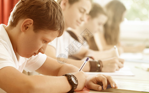 学生或学生在学校写作考试集中学习孩子们女孩们教学教育男孩们测试队友青年班级背景图片