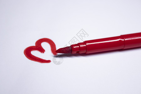红色墨水旁边画着一颗心的红色毡尖笔 文具的概念 复制空间 隔离背景