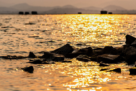 水中的岩石在阳光下反射着黄色的光芒高清图片