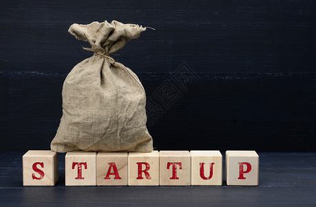 完整的帆布袋和带有 Startup 字样的木制立方体 创业 投资的筹款理念背景