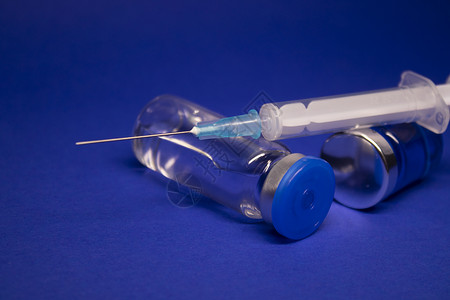 安卓开发两个没有标签的透明疫苗瓶小瓶 医用注射器注射针 在蓝色背景上隔离 冠状病毒疫苗 COVID19 的开发 治愈 世界研究竞赛横幅技背景