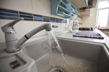 在厨房里 水从水龙头流进水槽流动的高清图片素材