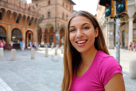 梁哥鸡窝发型在中世纪意大利街上行走的美丽微笑的年轻女子的肖像长发快乐女士拉丁皮肤城市女性街道头发女孩背景