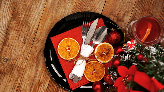 圣诞餐巾圣诞晚餐装饰 配有干橙子和黑色餐盘上的红餐巾纸装饰品桌布庆典星星卡片刀具食物假期银器勺子背景
