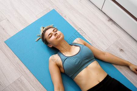 腹式呼吸法锻炼后躺在瑜伽垫子上的美丽年轻美女的顶端景色力量女孩健身房压力黑发地面福利理念护理调息背景