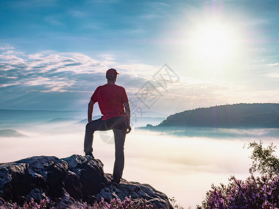 一个人站在一块岩石上 由云层环绕 在山顶上漫步阳光浓雾日落环境水池活动天气好奇心山峰成人背景图片