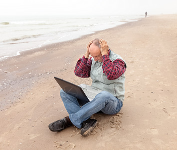 在海滩上拿着笔记本的老头商务在线技术办公室自由职业者互联网公室闲暇工人商业背景图片