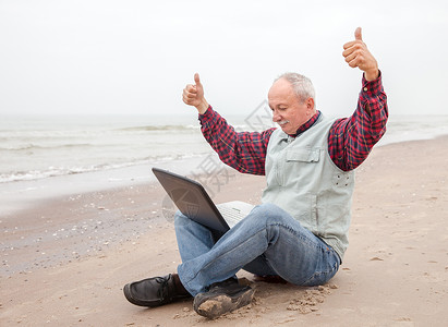 在海滩上拿着笔记本的老头生活在线闲暇自由职业者老年人士公室职场互联网男人背景图片