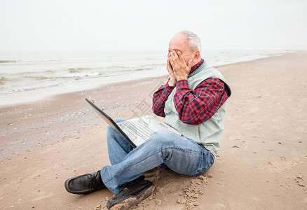 在海滩上拿着笔记本的老头办公室男人闲暇人士老年商业技术男性公室电脑背景图片