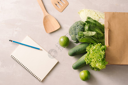 纸袋里装满了健康食品 有灰色背景的笔记本 顶部视图 平面花园营养绿色食物农业饮食托盘黄瓜盒子排毒背景图片
