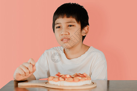 吃饱饭男孩亚洲可爱男孩坐在饭桌上 前面桌子上披萨吃着比萨背景