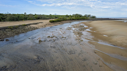 在低潮下 空中看到一条小溪 与泥土和沙滩在阴云的蓝色天空下 澳大利亚帕尔默斯顿角背景