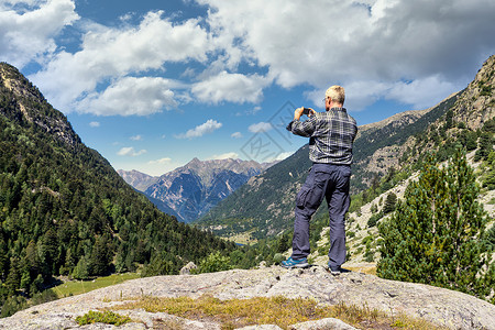 中年旅游男子用手机在山上拍一张相片高清图片