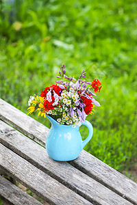 蓝色花瓶在木凳上的蓝色陶瓷花瓶里 盛满鲜花花束婚礼植物群玻璃桌子花瓣园艺树叶礼物植物背景