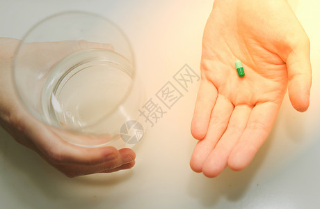 药物水妇女手持避孕药片 在为保健而服用医药胶囊之前 补充抗氧化剂维生素矿物质胶囊和水杯背景