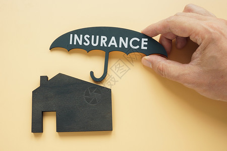家庭保险概念 手持伞盖在房子上高清图片