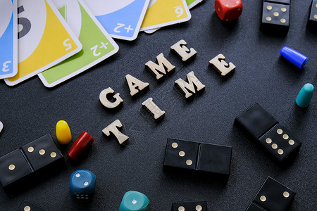 糯米诺骨牌基辅乌克兰 - 10 03 21 文本游戏时间用木字拼写出来 被黑色背景上的骰子游戏纸牌包围 桌上游戏 待在家里活动背景