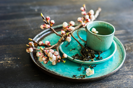 绿茶和桃花作为春季概念筷子树叶茶叶粉笔樱花玻璃饮食餐巾杯子勺子背景图片