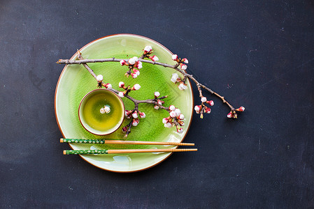 绿茶和桃花作为春季概念筷子餐巾杯子茶叶玻璃樱花粉笔树叶饮食饮料背景图片