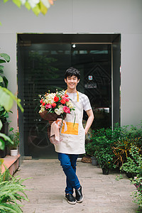 男花店员在工作场所持有鲜花装饰女士风格职业工作店铺植物群花朵花束职场背景图片