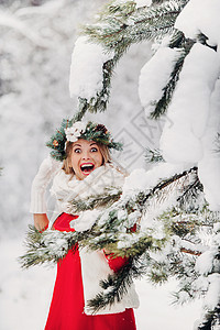 红色新品爆炸贴在寒冷的冬季森林里穿着红色夹克的女人的画像 在白雪覆盖的冬季森林里 头戴花环的女孩假期女士新品帽子裙子季节衣服花园新年雪花背景