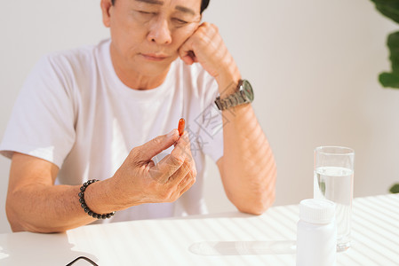 可怜的老人在家中吃药时不开心的老男人男人制药药店药物退休男性老年悲伤背景图片