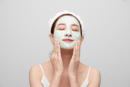 韩国面膜素材满意女人的长相改善了皮肤状况 戴着面罩 用白色背景触摸脸颊和脸部清洁女士治疗黏土健康面具温泉女性沙龙化妆品背景