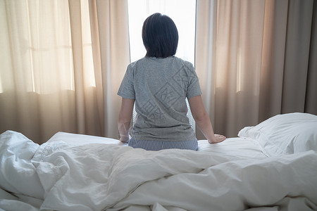 背对着女人的眼神 感到沮丧和坐在床上情感房子挫折女性悲伤女士孤独者房间女孩失败背景