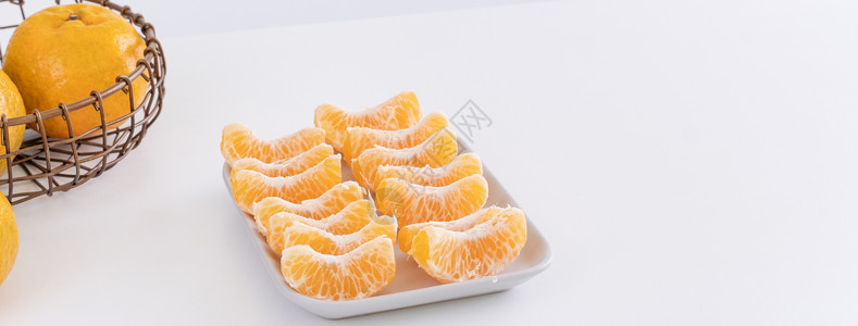 片篮子里的茼蒿图片盘子里漂亮的去皮橘子和金属篮子 在现代现代厨房岛的明亮白色干净桌子上隔开食物水果热带果汁橙子月球摄影背景