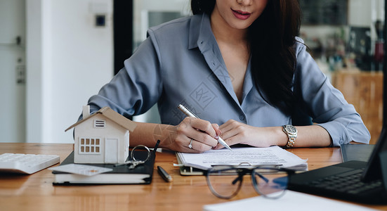 商业女商务人士手在租赁家庭文件上签字 并有一套公寓钥匙作为文书金融的高清图片素材