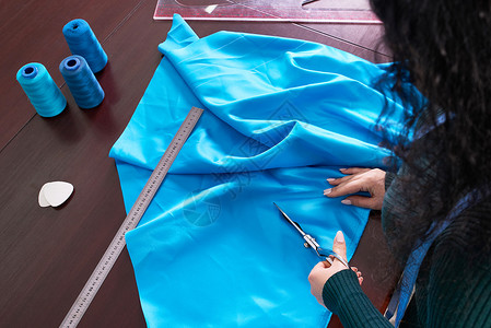 在裁缝制衣室 餐饮店 切割蓝布的服装师剪切工作室女士女裁缝缝纫设计师工艺工具粉笔磁带背景图片