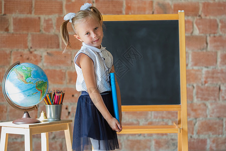 黑板视觉辅助Caucasian学校幼稚园女孩的肖像 她手里拿着书背景