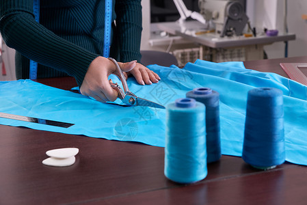 在裁缝制衣室 餐饮店 切割蓝布的服装师工艺职业工作室缝纫粉笔桌子工作衣服设计师维修背景图片