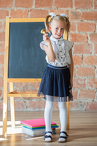 穿着校服的可爱小女孩 坐在学校董事会旁边 带着铃声高清图片